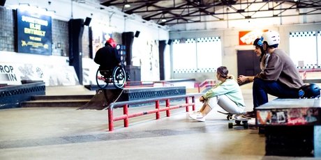 Skatehalle Berlin: Dos patinadores observan el patinaje en silla de ruedas