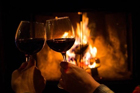 Couple holding pair of glasses with wine at fire pit