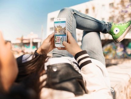 Young woman uses street art highlight of the ABOUT BERLIN app.