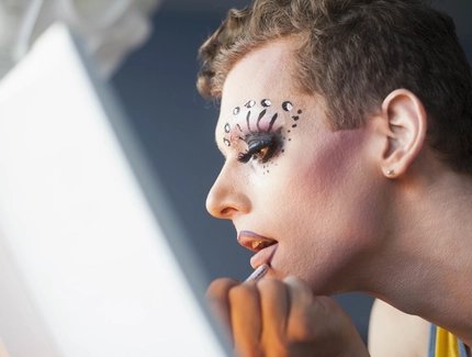 Drag queen maquillándose frente al espejo