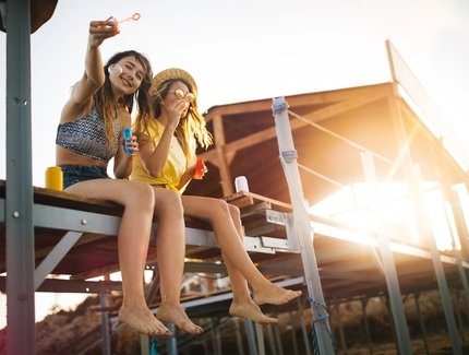 Beautiful young hipster women on summer vacations blowing bubbles