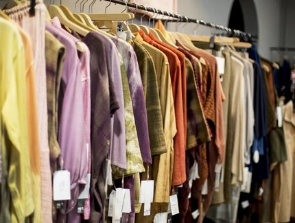 Ropa colgada en perchas de colores en una tienda.