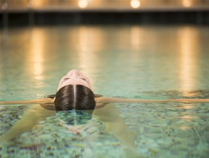 Una mujer se relaja en la piscina de un spa diurno